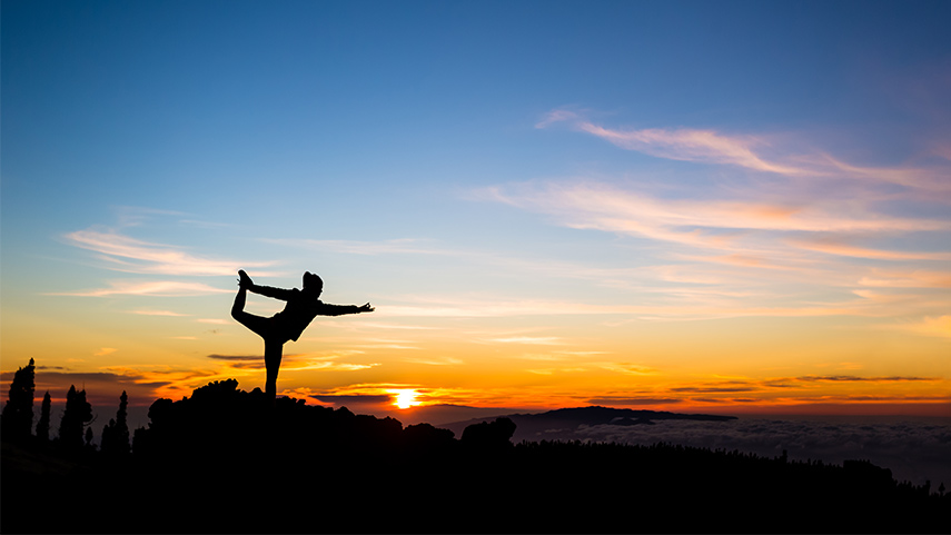 Femme au sommet d'une colline faisant des exercices de yoga