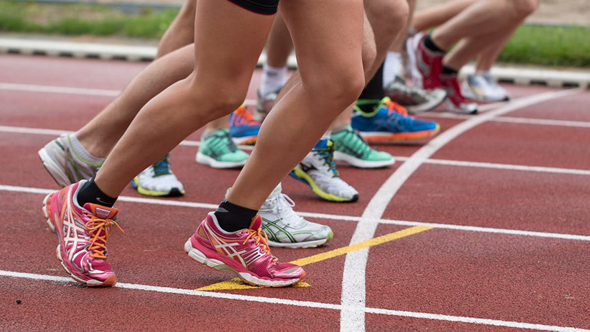 Les athlètes sur la ligne de départ se préparent à courir sur une piste, en se concentrant sur leurs jambes et leurs chaussures de course.